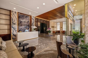 A hotel lobby with a reception desk, seating area, and a 'Welcome Danang Petro Hotel' sign.