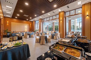 A spacious banquet hall with high ceilings, large windows, and a buffet setup. - Danang Petro Hotel (Da Nang)