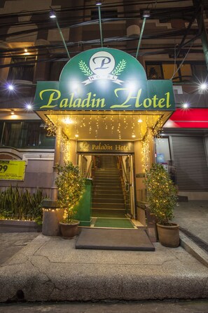 La façade de l’hôtel Paladin, avec son panneau indicateur, son entrée et ses éclairages décoratifs.