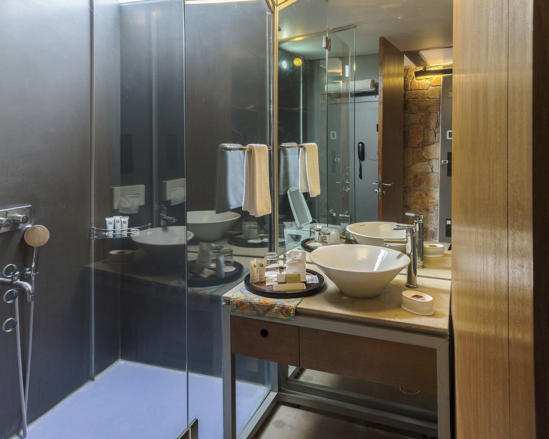 A modern bathroom with a glass shower enclosure, two sinks, and a wooden vanity.