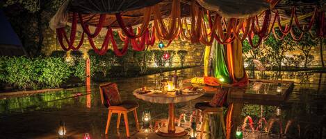 An outdoor dining area with a round table, chairs, and string lights.