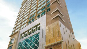 A tall, modern building with a distinctive architectural design, featuring a mix of glass and patterned facades. - Ramada Hong Kong Harbour View (Hong Kong)