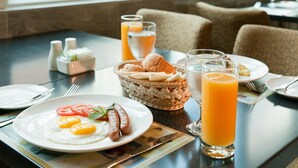 A breakfast setting with plates of eggs, sausages, and toast, a basket of bread, and glasses of orange juice. - Ramada Hong Kong Harbour View (Hong Kong)