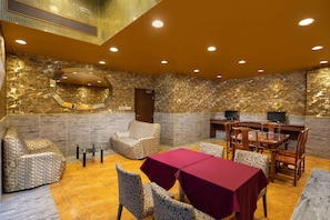 A restaurant with a stone wall backdrop, a wooden dining table, and patterned chairs.