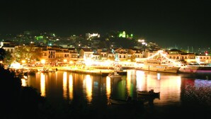 A waterfront town at night with illuminated buildings and boats docked along the harbor.