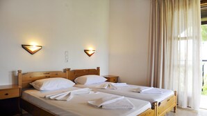 A double bed with white linens and towels, wooden headboard, bedside tables, and wall-mounted lights.