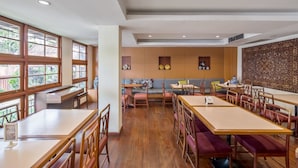 A spacious restaurant with wooden tables and chairs, a seating area with cushions, and large windows allowing natural light. - JL Bangkok (Bangkok)