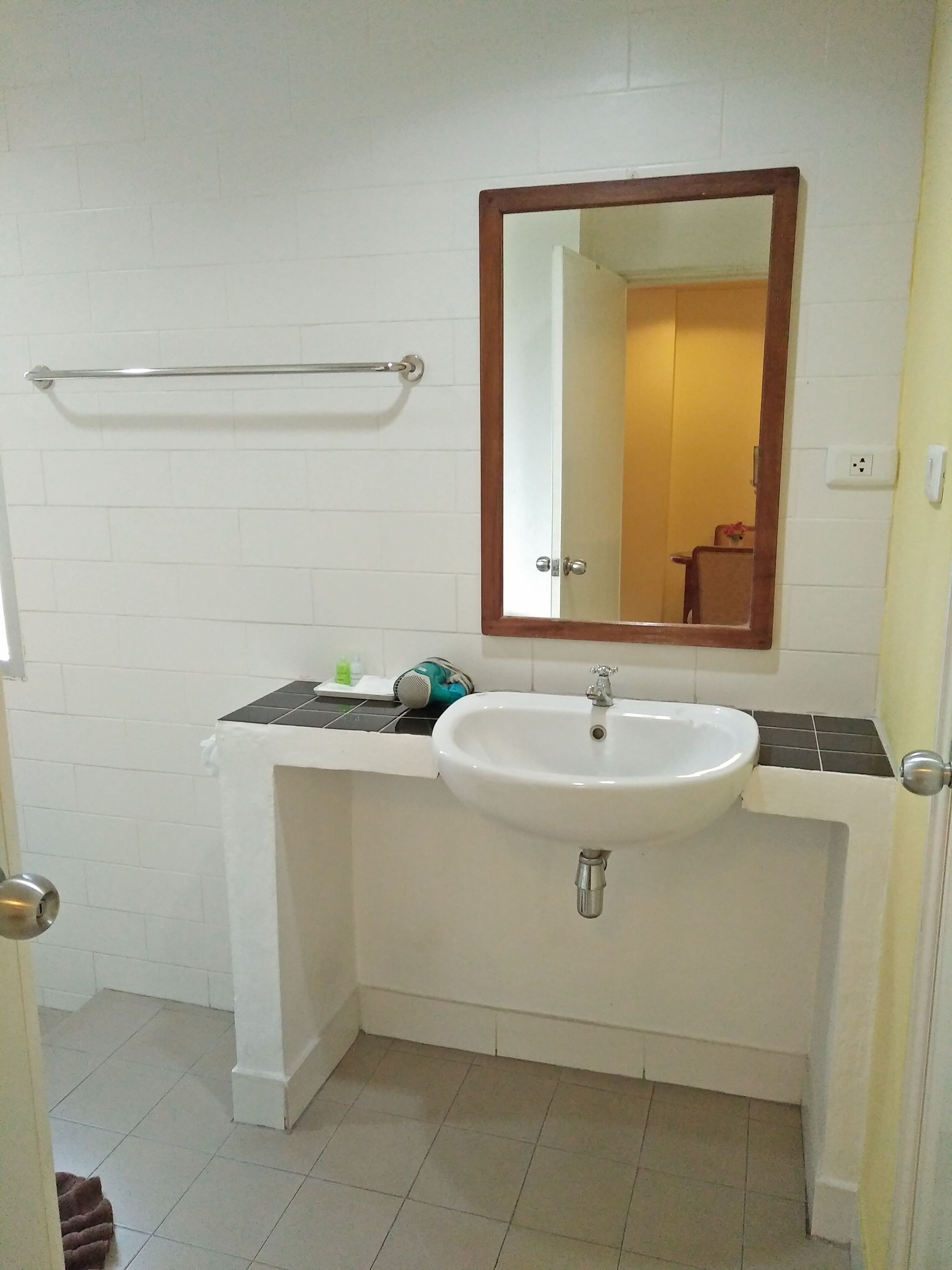 A bathroom with a white sink, a mirror, and a towel rack.