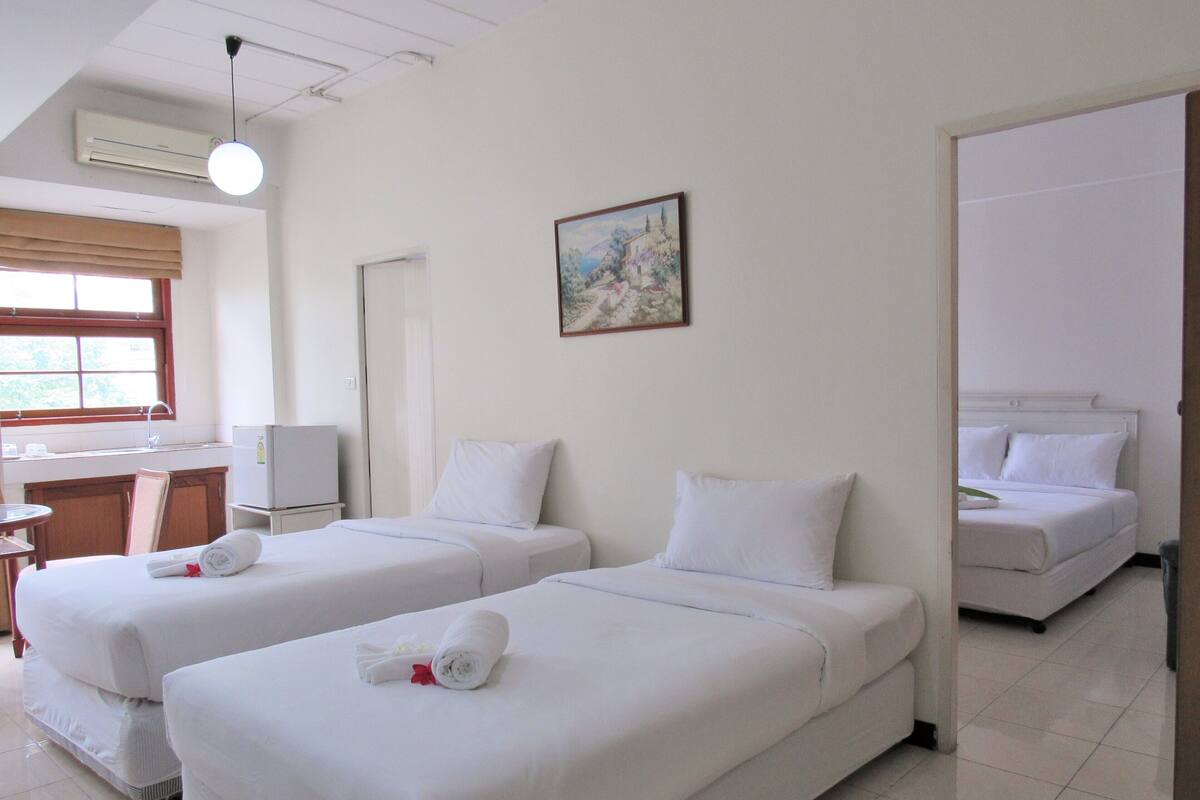 A hotel room with two beds, a desk, a chair, and a painting on the wall.