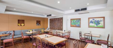 A restaurant with wooden tables and chairs, a sofa, and decorative wall panels.