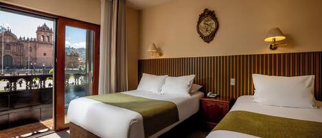 A hotel room with two beds, a view of a historic building, and a balcony.
