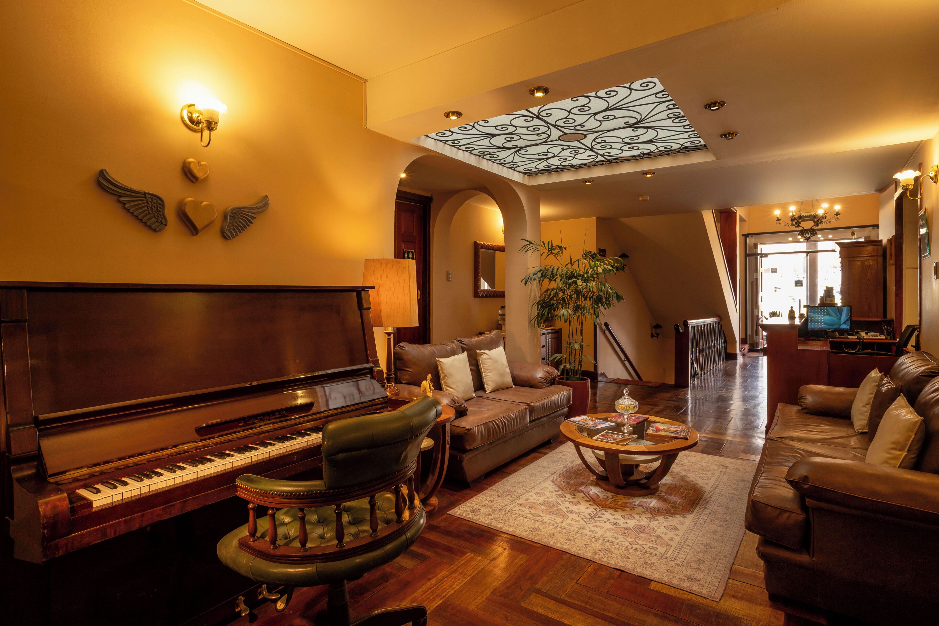 A spacious living room with a grand piano, leather sofas, a coffee table, and a decorative ceiling.