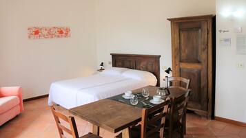 Ein Schlafzimmer mit einem Bett, einem Holztisch mit Stühlen, einem rosa Sessel und einem Holzschrank.