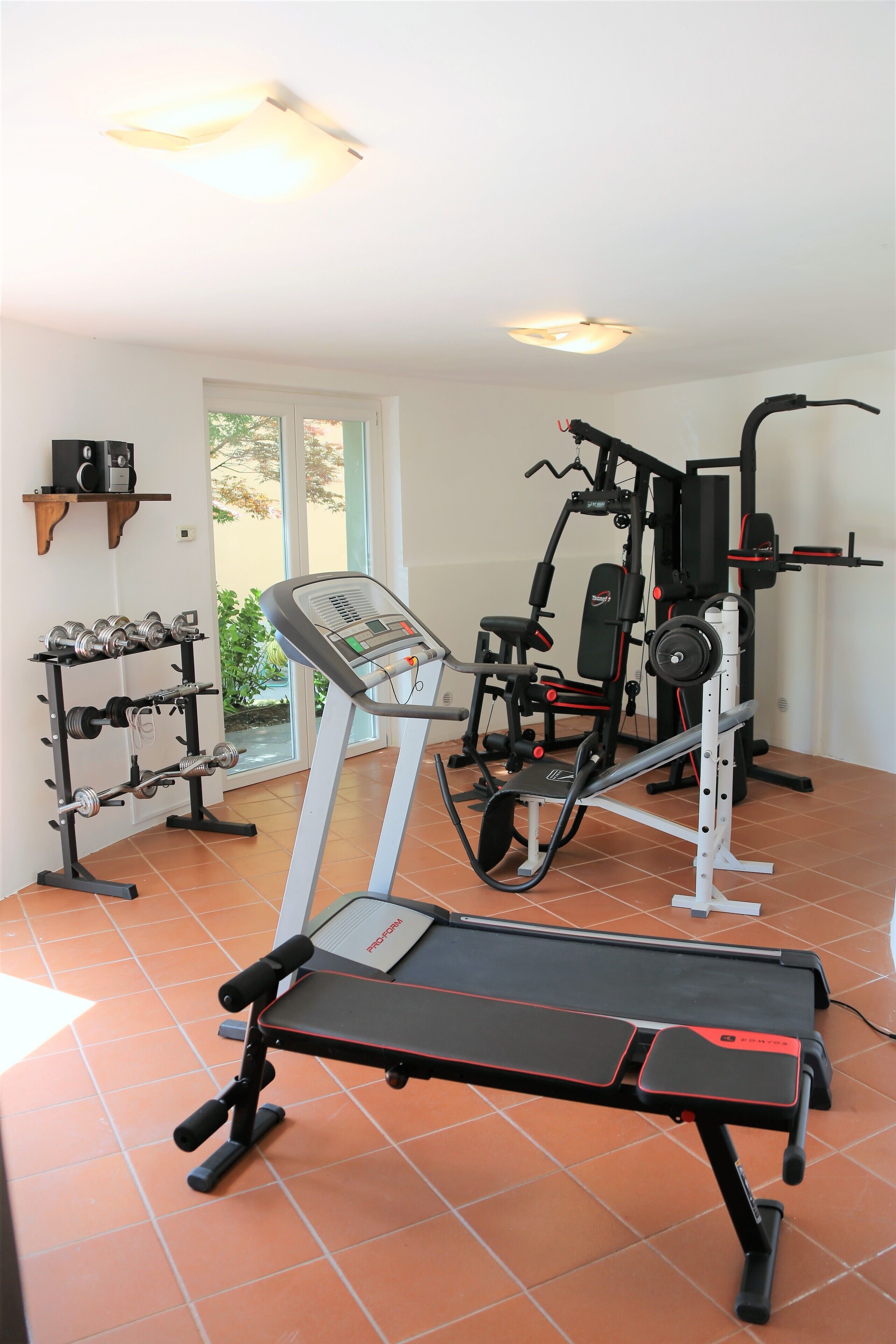A home gym with a treadmill, weight bench, and various exercise equipment.