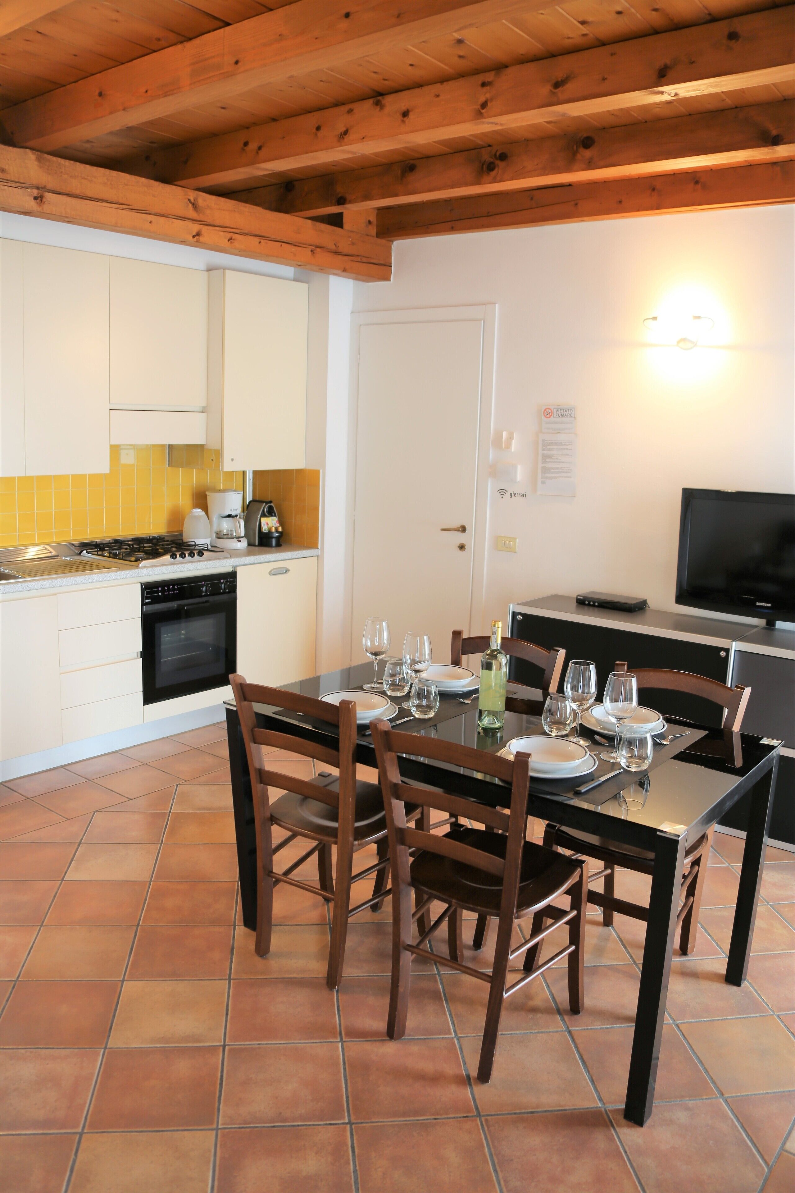 A modern kitchen with white cabinets, a stove, and a dining table set for four.