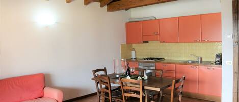 Una cocina con armarios de madera, una mesa de comedor con sillas y un sofá rosa.