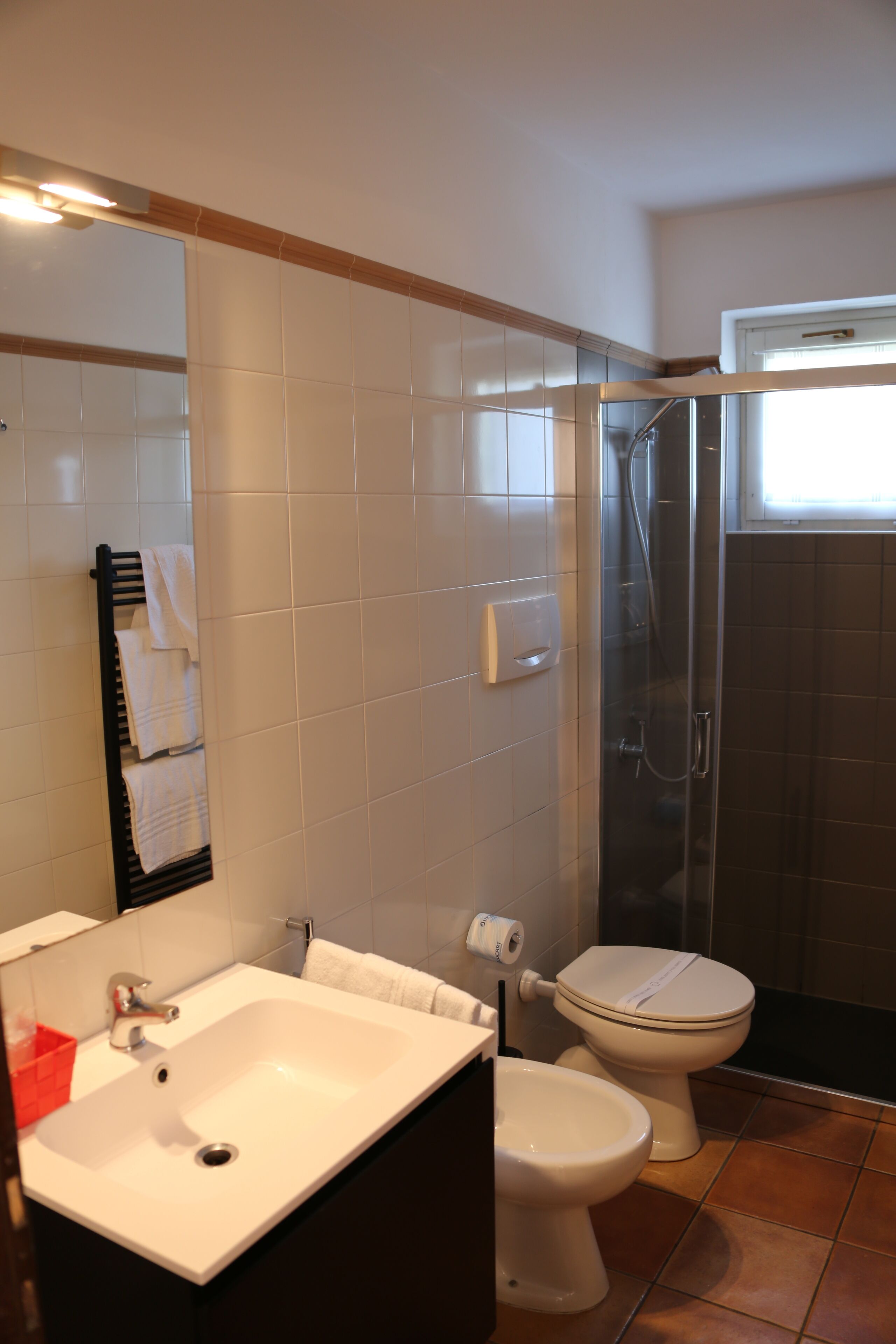 A bathroom with a white sink, toilet, and shower enclosure.