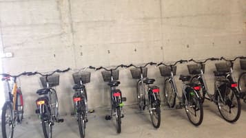 A row of bicycles parked against a wall with numbered slots.