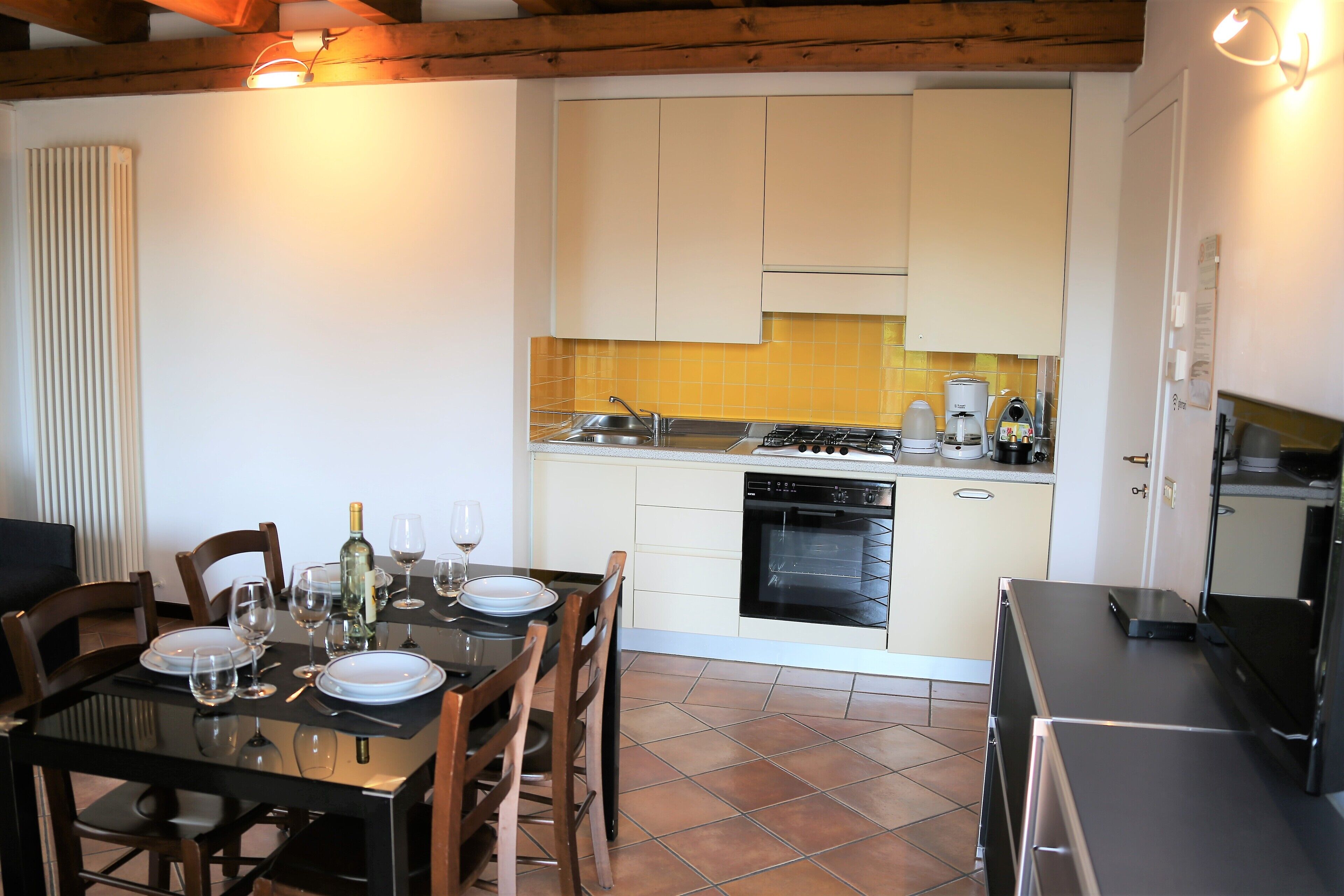 Una cocina compacta con muebles blancos, estufa a gas y lavavajillas.