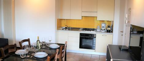 A compact kitchen with white cabinets, a gas stove, and a dishwasher.
