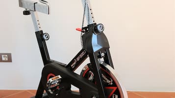 En stillestående motionscykel med digital skærm, styr og sadel.