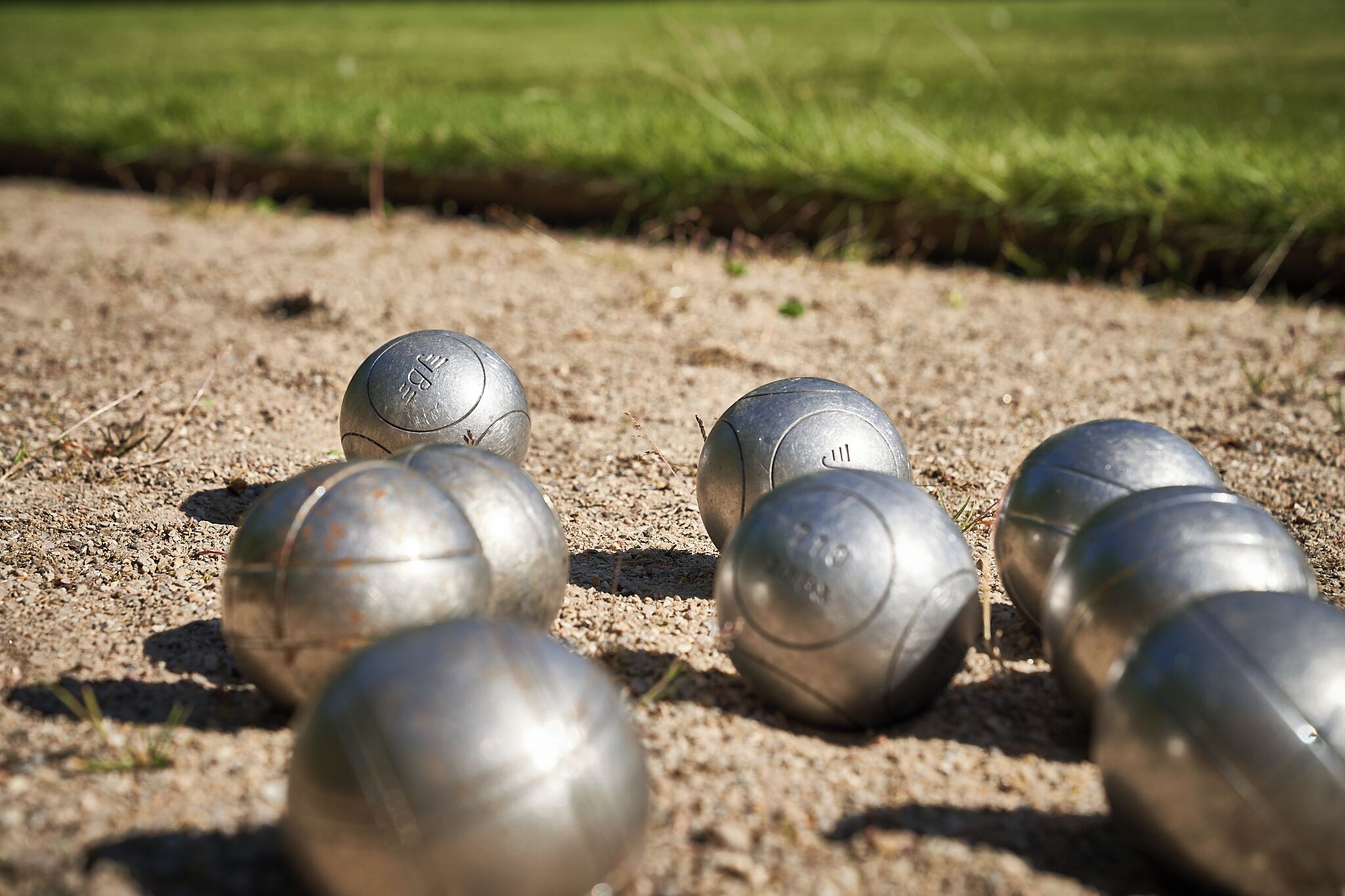 Et nærbillede af metalgolfbolde på en sand overflade.