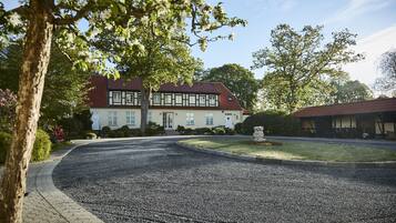 A traditional building with a symmetrical facade, a gravel driveway, and a well-maintained lawn.