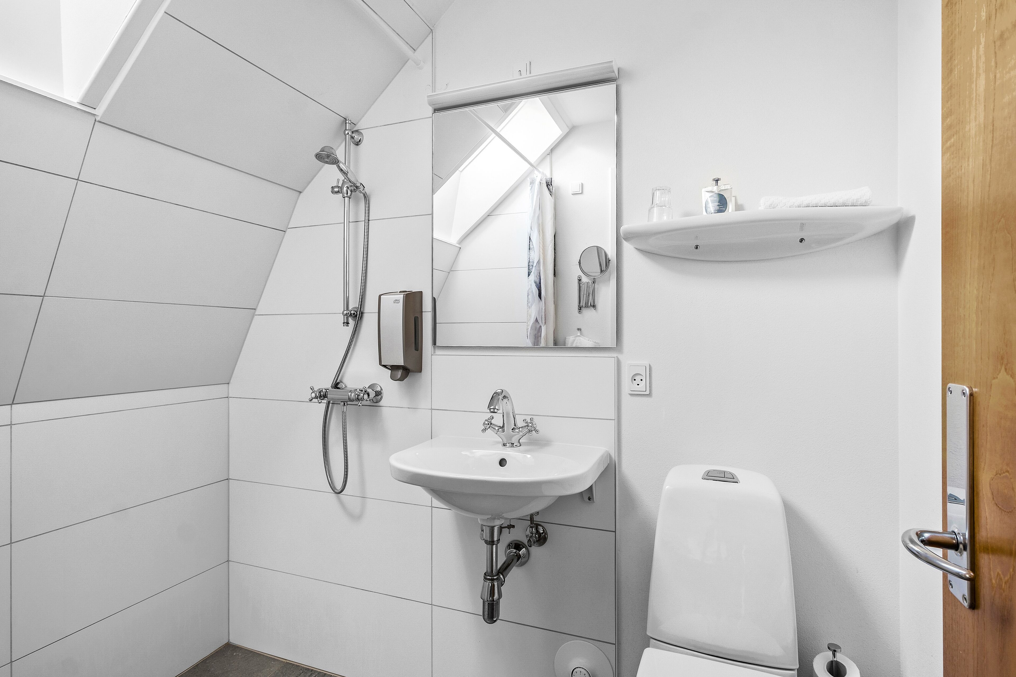 Un baño moderno con ducha, lavabo, inodoro y espejo.