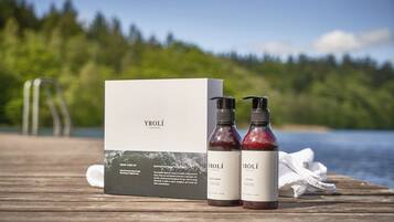 A wooden deck with a box and two bottles labeled 'YROLÍ' on a lakeside setting.