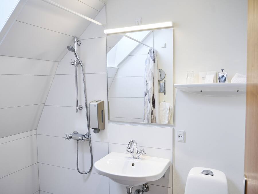 Un baño moderno con ducha, lavabo y espejo.