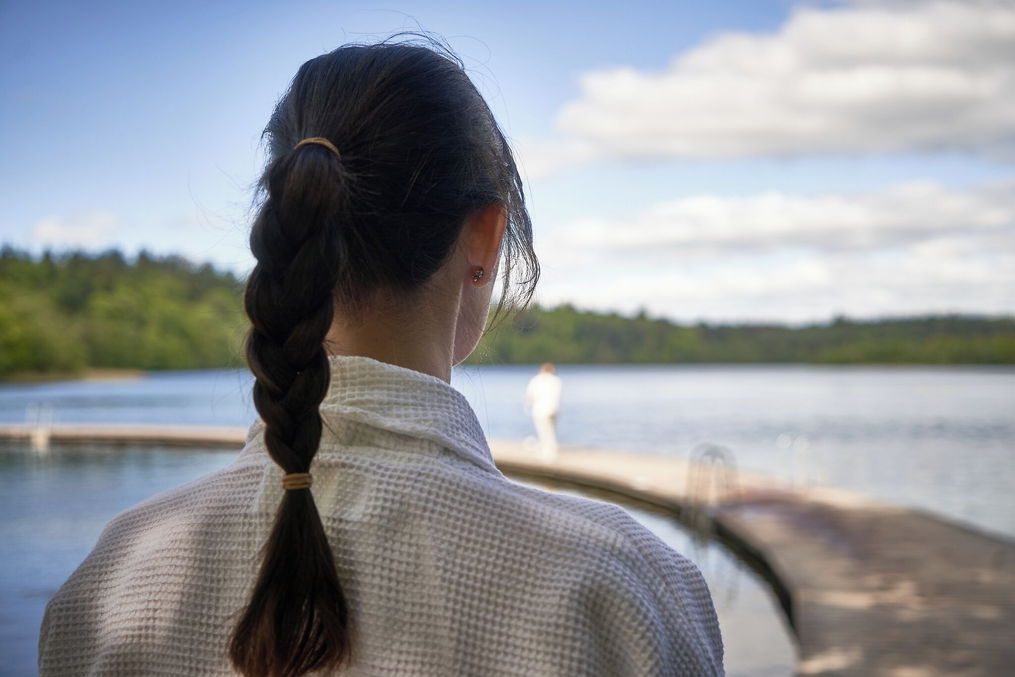 A person with a braided ponytail looking out over a body of water.