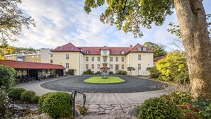 A large building with a central courtyard, surrounded by well-maintained gardens and a stone pathway leading to the entrance. - Gl. Skovridergaard (Silkeborg)