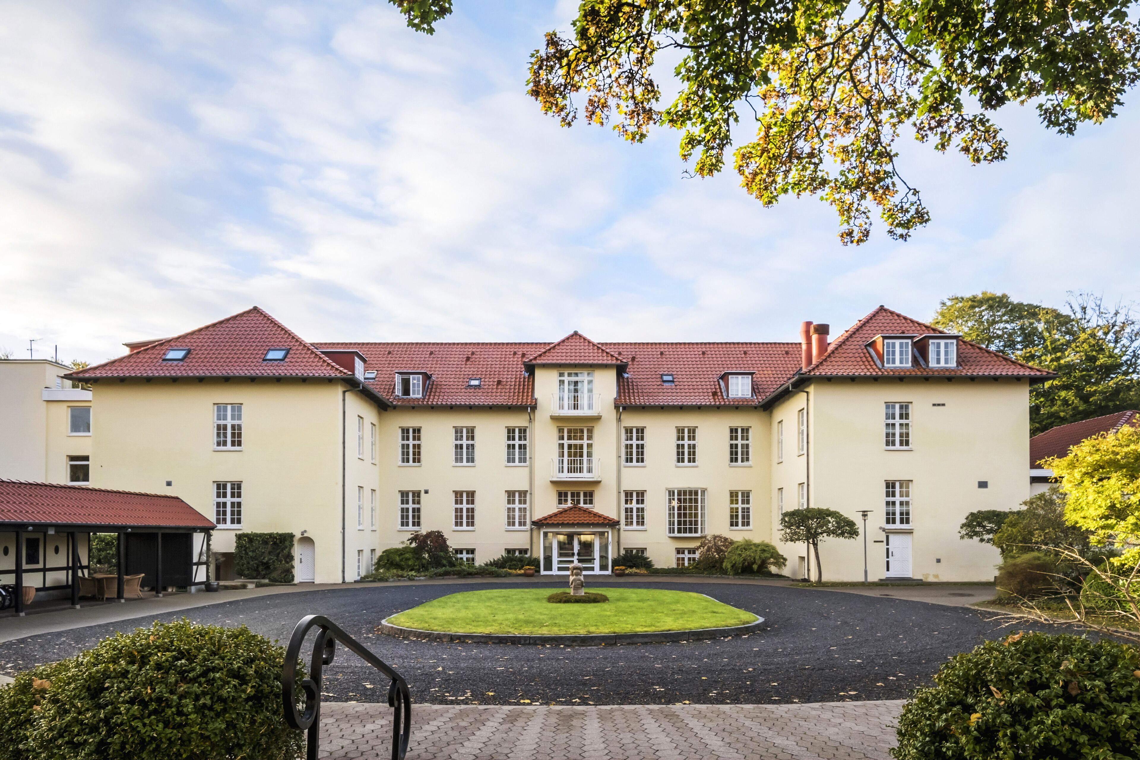 A large, symmetrical building with a central entrance, multiple windows, and a paved courtyard.