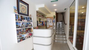 A reception area with a counter, a staircase, and a wall with bookshelves. - Royal Inn Aparthotel (Lloret de Mar)