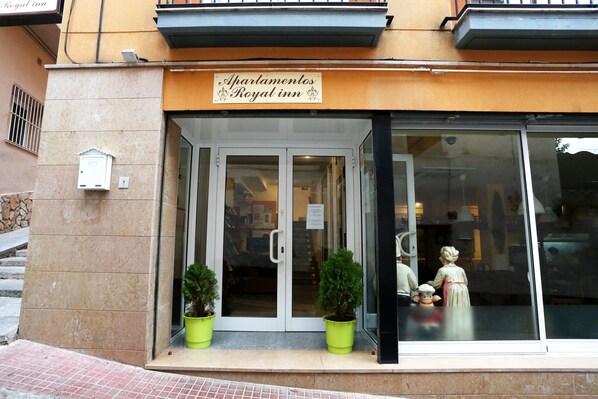 A hotel entrance with a sign reading "Apartamentos Royal inn".