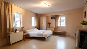 A bedroom with a bed, bedside table, chair, wardrobe, and a television on the wall. - Royal Inn Aparthotel (Lloret de Mar)