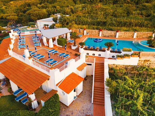 A resort with multiple swimming pools, sun loungers, and a staircase leading to a rooftop area. - Poggio Aragosta Hotel & Spa (Casamicciola Terme)