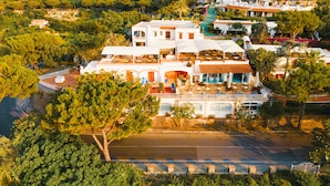 Un edificio grande y blanco con varios niveles, zonas de estar al aire libre y una piscina.