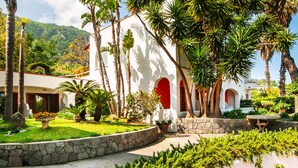Un resort con piscina, palmeras y un edificio blanco con detalles rojos.