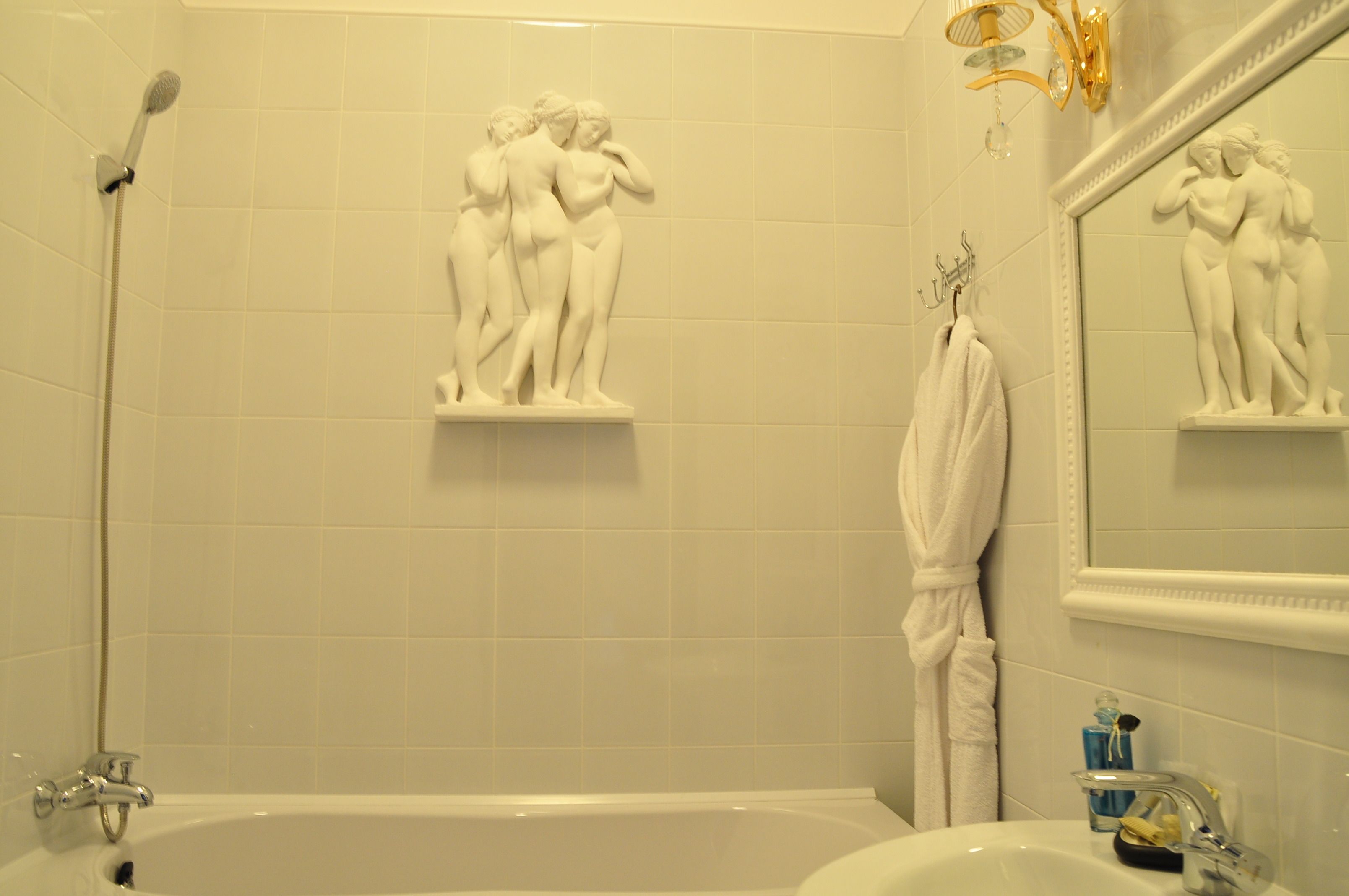 A bathroom with a bathtub, a shower, and a sink. There are two wall-mounted sculptures, one above the bathtub and one above the sink.