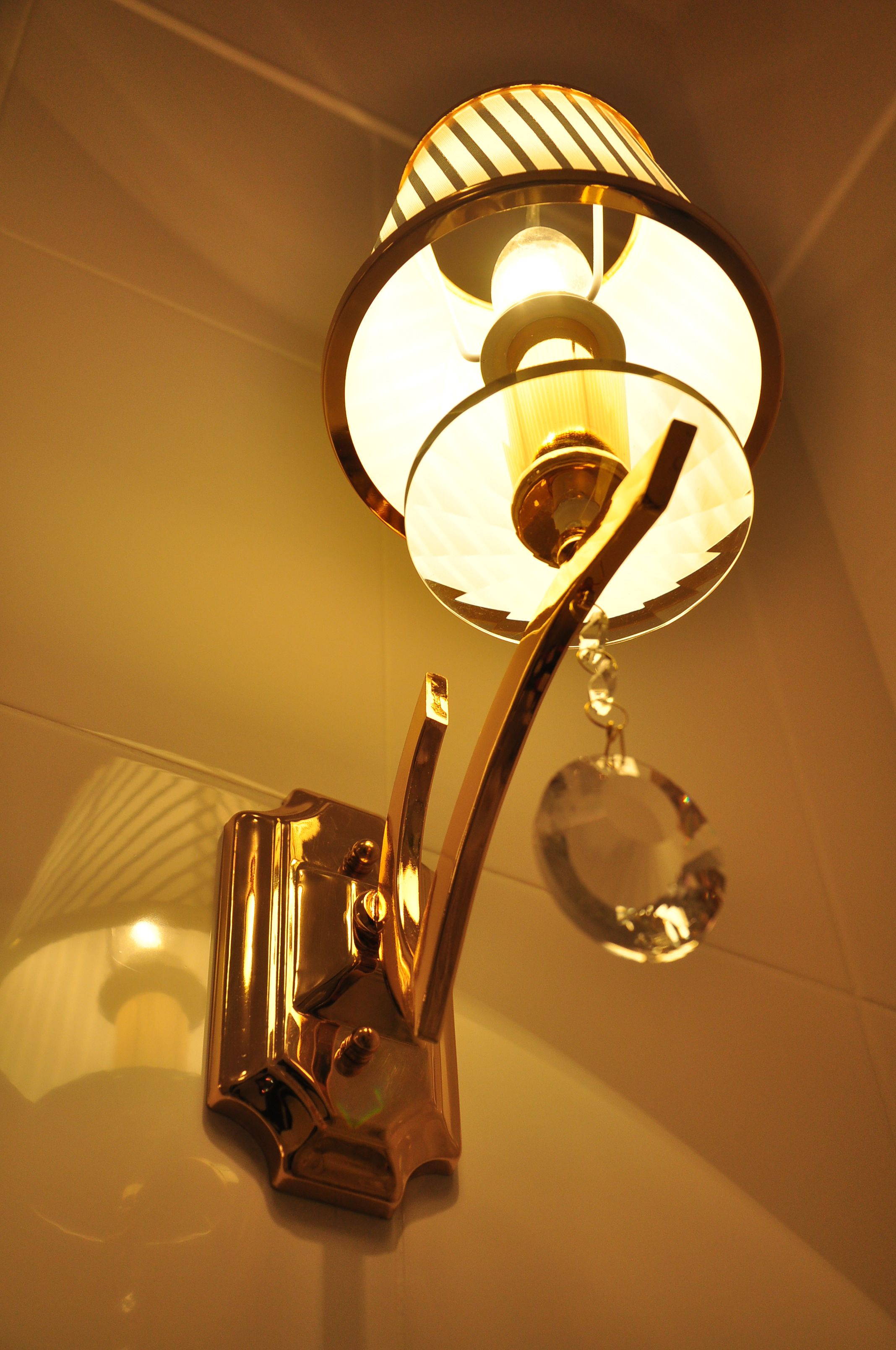 A wall-mounted light fixture with a cylindrical shade and a metallic base.
