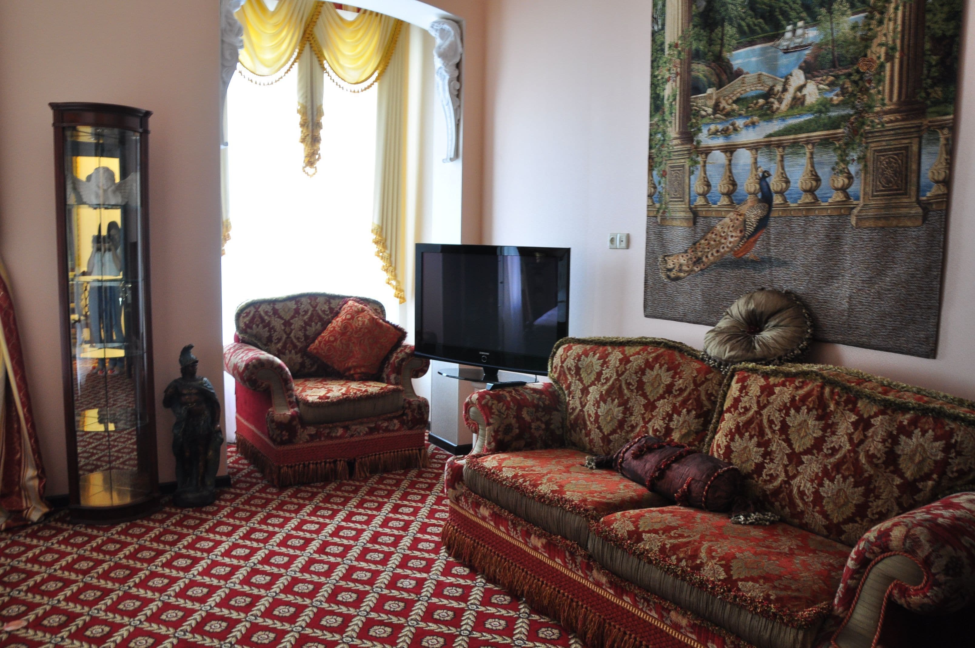 A traditional living room with ornate furniture, a television, and a large decorative painting.
