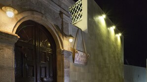 A stone building with a dark wooden door, a sign reading "Boutique Furniture," and a light fixture above the door. - Lindos Boutique Rooms - Adults Only (Rhodes)