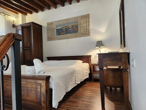 Une chambre à coucher avec un lit en bois, une table de chevet, une lampe et un tableau accroché au mur.