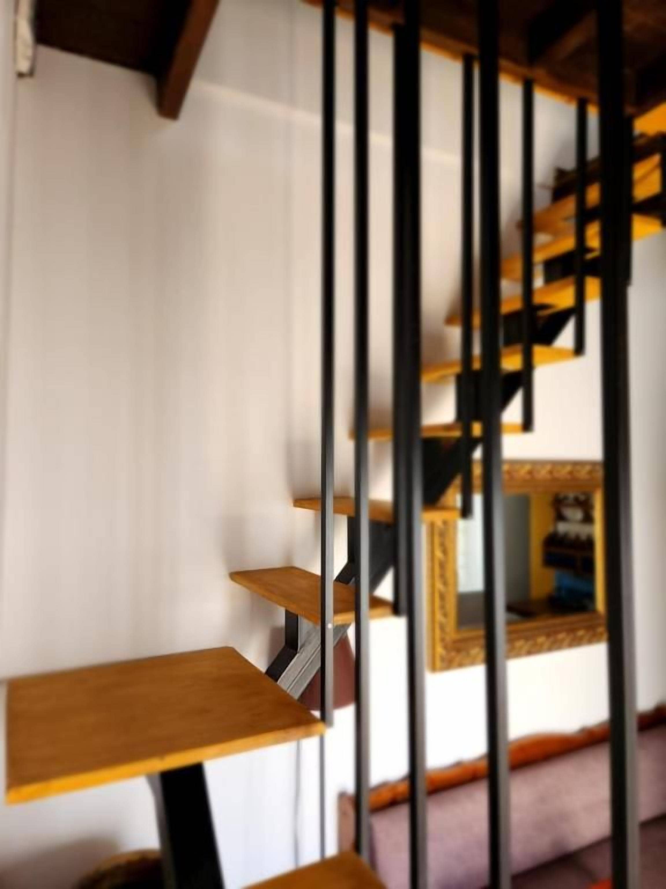 A staircase with wooden steps and black metal railings.