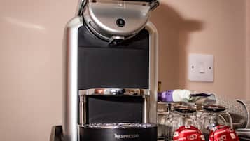Une machine à café Nespresso, avec un présentoir de capsules de café et un verre d’eau.