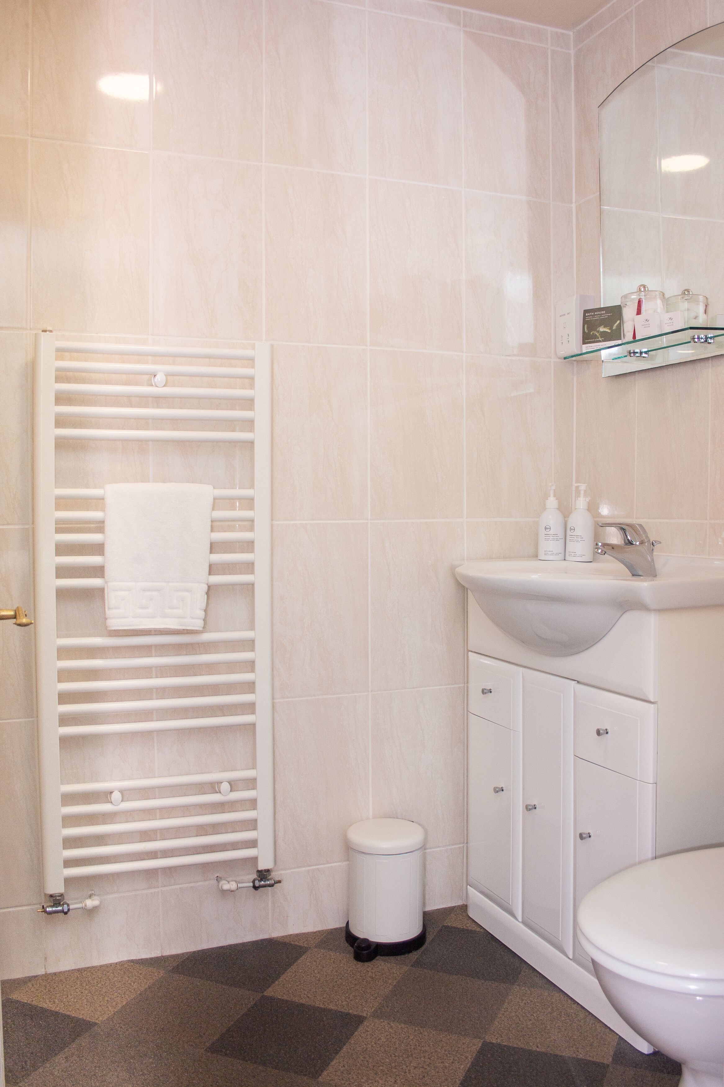 Un baño con lavamanos blanco, espejo y toallero.