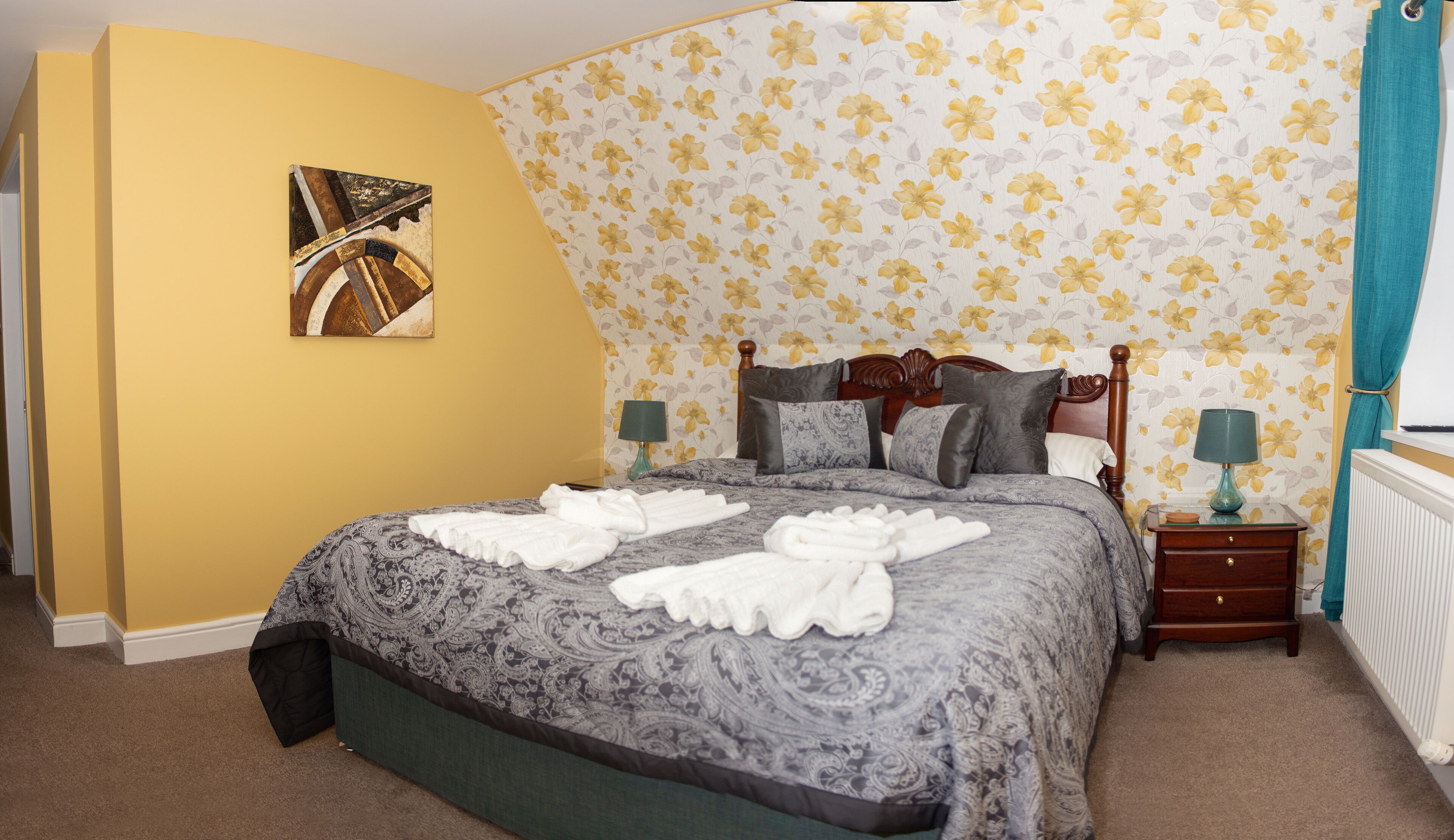 A bedroom with a bed, a nightstand, a lamp, and a painting on the wall.