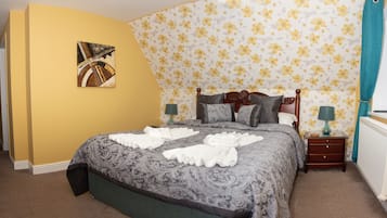 A bedroom with a bed, a nightstand, a lamp, and a painting on the wall.
