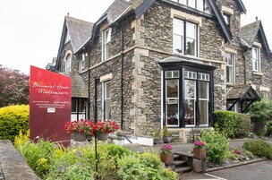 A stone building with a sign for Beaumont House Windermere, including contact information and a website.